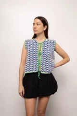 Chaleco tejido a mano en crochet con hilado 100% algodón, color azul con detalles en blanco y terminaciones en verde. Diseño reversible con lazos de ajuste frontales.