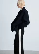 Pantalón de punto fino negro con raya lateral blanca, tiro medio, diseño recto y largo.