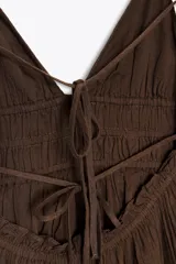 Vestido midi marrón con escote en V, tirantes finos ajustables y espalda descubierta con lazadas.