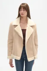 Campera tipo aviador de poliéster en color natural con forro de piel sintética a contraste. Presenta cuello de solapa, cierre frontal asimétrico con cremallera, bolsillos laterales con cierre y detalle de cremalleras en los puños.