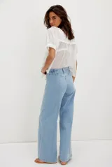 Pantalón de jean de tiro alto, color celeste claro, con corte ancho y costura central vertical que recorre la pierna.