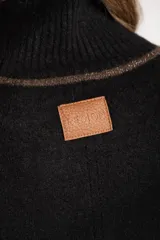 Sweater negro de tejido grueso con cuello alto acanalado. Presenta una franja decorativa en las mangas y el cuello en hilo marrón con brillo (lurex).