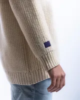 Sweater unisex color crema de lana merino, con cuello redondo y corte holgado.