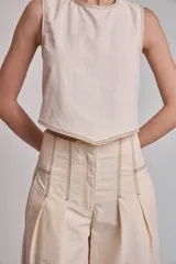 Blusa corta color marrón, sin mangas, con cuello redondo y pespuntes en contraste color blanco.