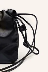 Bandolera negra de cuero ovino con fruncido superior y correa ajustable.