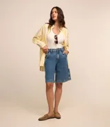 Camisa de viscolino con estampado de rayas verticales amarillas y blancas, corte alargado, cuello inglés, mangas largas y bolsillo en el pecho.