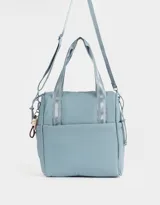 Cartera shopper negra de tela deportiva con doble asa corta estampada, correa regulable y desmontable, cierre superior con puller de goma y charm lateral.