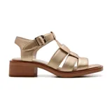 Sandalia de cuero sintético color dorado, con tiras anchas cruzadas en el empeine, hebilla lateral y taco cuadrado bajo.