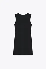 Vestido corto negro de punto, con cuello redondo y sin mangas. Tiene una abertura en el ruedo y detalle de botones metálicos irregulares cruzados en el lateral.