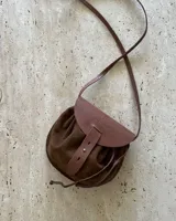 Bandolera marrón de cuero gamuzado con solapa de cuero liso y cierre con tira de cuero con botón a presión.