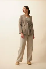 Chaqueta corta color beige, entallada, con escote en V, manga larga y cierre frontal con lazo fijo. Confeccionada en lana fina sin teñir, con bolsillos escondidos y terminaciones enviadas. Hecha 100% en Uruguay.