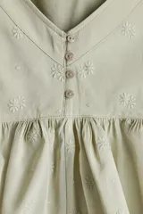 Top verde claro con breteles finos, escote en V, abertura con botones y peplum con leve vuelo.
