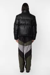 Campera puffer negra de cuerina PU opaca, corte boxy fit, cuello alto con elástico y tancas metálicas, acceso delantero con cierre metálico desmontable y tiracierre de marca, bolsillos ribete con snap metálico y bolsillo superior con cierre metálico cubierto por vista y avío marcario, mangas desmontables por cierre de nylon cubierto con vista, terminaciones de mangas y cintura con elástico interno, forrería al tono, cinta gross estampada nombre de marca y snaps en sus extremos para transportarla al hombro, bolsillo interno de tela base con cierre invisible.