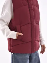 Chaleco negro acolchado con capucha y diseño sin mangas, ideal para superponer.