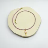 Collar corto de cuentas color lila con dije de pez esmaltado en amarillo y rosado.