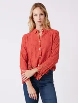 Camisa de algodón color naranja, con bordado suizo y encaje calado. Tiene cuello con solapa, botones frontales, mangas largas con terminación de encaje y ruedo asimétrico con galón de encaje.