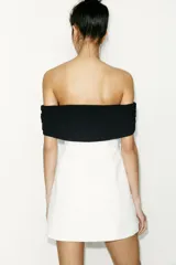 Minivestido blanco con escote recto palabra de honor con banda superior negra fruncida, corte ajustado y cierre lateral con cremallera oculta.
