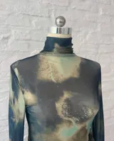 Minivestido de microtul elastizado con estampado abstracto en tonos verde, marrón y azul. Diseño ajustado al cuerpo, cuello alto y mangas largas.