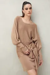 Vestido corto color dorado de punto con brillo integrado en la trama. Diseño de mangas amplias, falda ajustada y lazo frontal que acentúa la cintura.