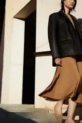 Blazer marrón de cuero sintético con solapas de muesca, cierre con tres botones, bolsillos delanteros con solapa y forro de sarga.