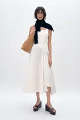 Vestido midi color blanco con finas rayas verticales en color gris, de escote cuadrado y tirantes anchos. Detalle de pliegue en delantero y cierre lateral con cremallera oculta.