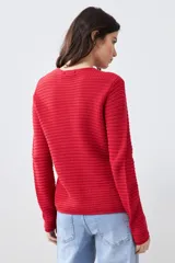 Chaqueta tejida roja con botones metálicos dorados y cuello redondo.