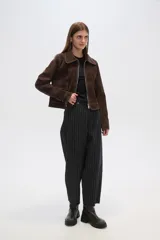 Chaqueta marrón de gamuza con cuello camisero, cierre frontal con cremallera, bolsillos de parche y costuras en contraste.