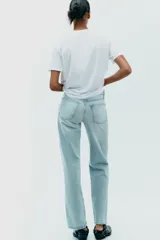 Camiseta blanca de algodón con cuello redondo, manga corta y apliques de lazos de raso blancos en el frente.