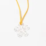 Collar con dije de flor transparente y cordón fino color mostaza.