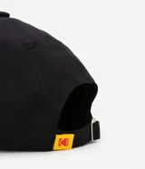 Gorra negra de sarga de algodón con visera curva, hebilla ajustable y logo de Kodak bordado en amarillo y rojo.