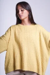 Sweater oversize tejido en punto trenzado color gris, con cuello redondo y mangas largas.