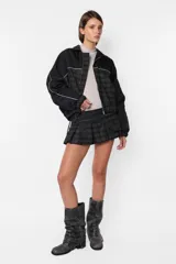 Minifalda gris con estampado de cuadros escoceses, cintura ancha, tablas en la parte inferior y cierre metálico lateral. Incluye sobrefalda desmontable con bolsillo.