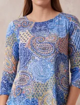 Blusa de modal estampada con motivos paisley en tonos azules, naranjas y amarillos. Tiene escote redondo y mangas tres cuartos.