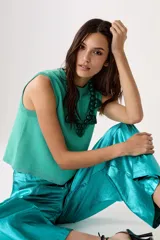 Top sin mangas color turquesa, tejido con lúrex para una textura brillosa y silueta holgada.