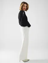 Buzo de tejido de punto color negro, con cuello redondo y mangas largas. Apliques de lentejuelas en los hombros. Marca Q2.