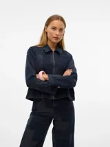 Camisa de denim azul oscuro con diseño patchwork de diferentes tonos de azul. Tiene cuello clásico, cierre frontal con cremallera dorada, mangas largas y corte holgado.
