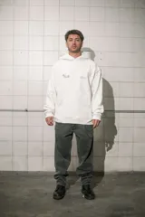 Hoodie color crema de algodón con capucha, bolsillo tipo canguro y estampado pequeño en el pecho.