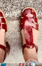 Sandalias rojas de cuero con tiras anchas y hebilla al tobillo.