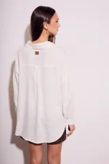 Camisa oversize color crudo, confeccionada en lino y viscosa, con cuello clásico, cierre frontal con botones de nácar y manga larga.