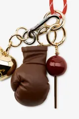 Llavero con cordón rojo y charms colgantes: corazón dorado, guante de boxeo marrón y esfera roja.