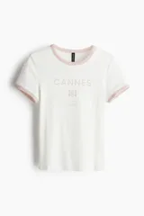 Remera blanca entallada corta en punto acanalado de algodón con estampado frontal "Cannes South of France" en color rosa.