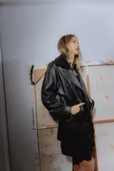 Campera bomber negra de cuero con cuello de piel sintética, forro interior y detalles de pasamanería en cuero marrón gastado.