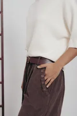 Pantalón de corte amplio color marrón, con cintura elastizada, detalle de botones en los laterales y cinturón incluido.