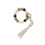 Llavero con pulsera de cuentas de silicona en color blanco, negro y animal print. Incluye un dije de flecos de cuero sintético color beige y un gancho metálico.