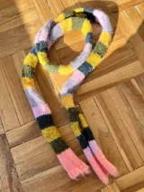 Bufanda angosta tejida a rayas horizontales en tonos rosa, lila, amarillo, verde y azul marino.