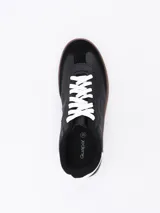 Zapatillas urbanas negras con cordones blancos y suela marrón.