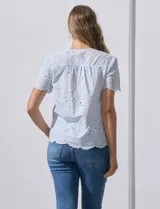 Blusa celeste de algodón con bordado broderie, cuello a la base con abertura central y botones.