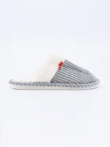 Pantuflas cerradas de tela de corderoy color gris, con interior de piel sintética blanca y detalle de moño rojo.