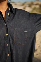 Camisa corta de jean celeste, de corte amplio, con cuello camisero, mangas largas abullonadas con puños elastizados, cierre frontal con botones y bolsillo plaqué en el pecho.