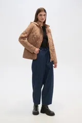 Campera blanca con diseño acolchado, cierre frontal con botones a presión y capucha desmontable.